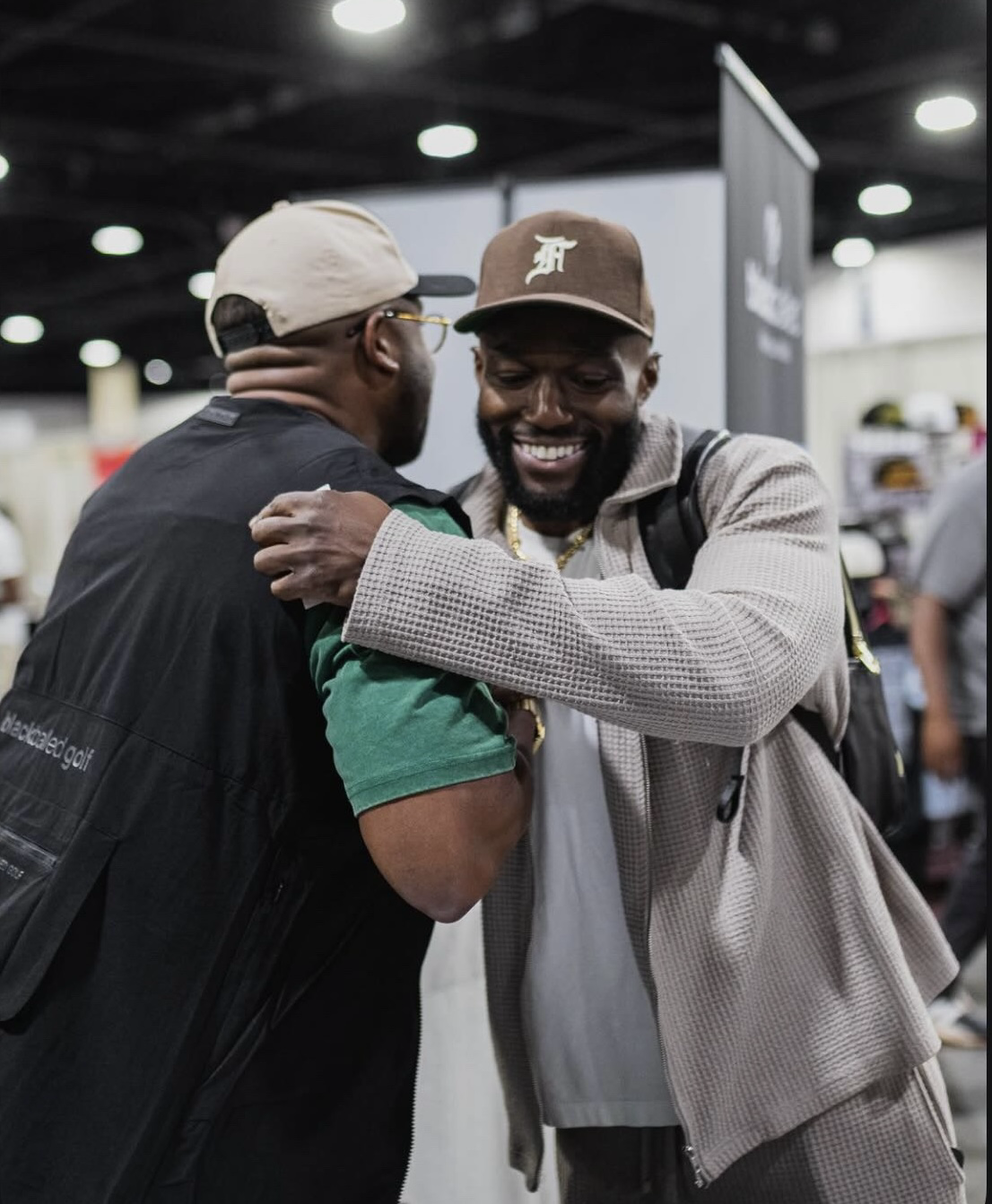 Two people greeting each other with a warm embrace at a busy networking event